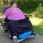Eine Frau in einem Sonderbau des LEO, der bis zu 400kg Zusatzlast tragen kann. Hierbei sind alle Maße breiter dimensioniert, um einen hohen Sitzkomfort zu gewährleisten.