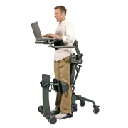 Ein Mann steht im EasyStand Evolv. Er arbeitet am Laptop, welcher auf dem integrierten Therapietisch steht.